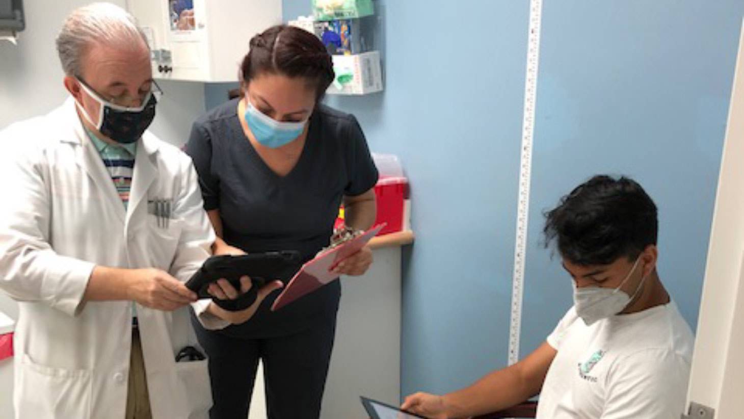 Patient reading tablet while medical personnel read a different tablet